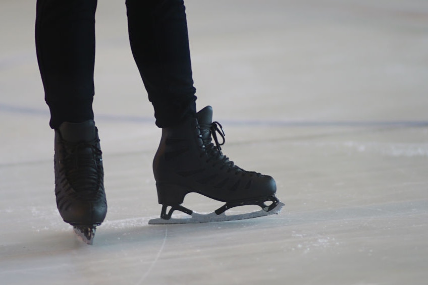 A close up of a figure skaters feet gliding across the ice.