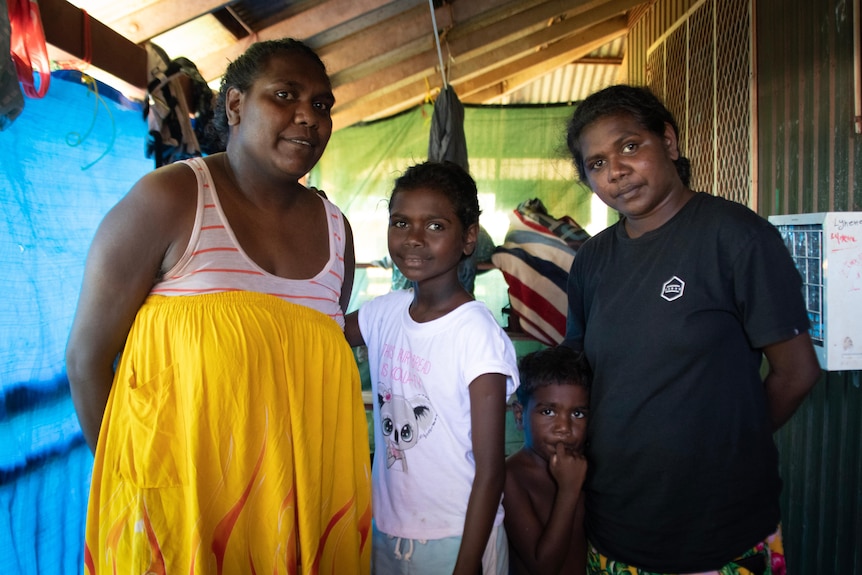 A portrait of a family standing on their verandah.