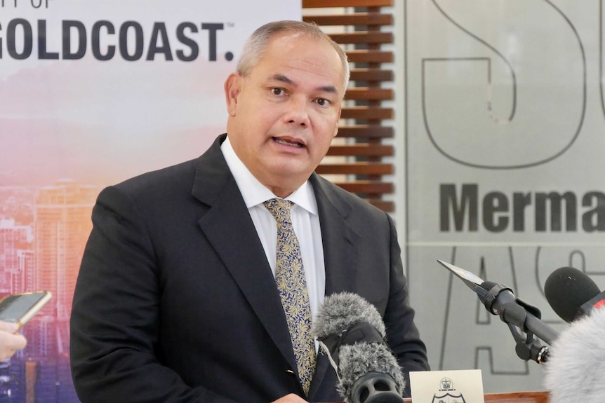 Gold Coast Mayor Tom Tate standing in front of media microphones.