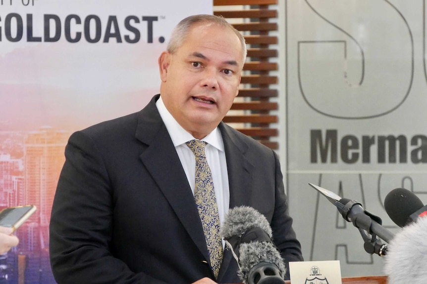 tom tate standing in front of media microphones