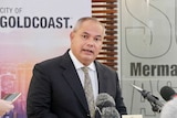tom tate standing in front of media microphones