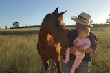 Grazier turned Federal election candidate wearing a cowboy hat while holding his daughter
