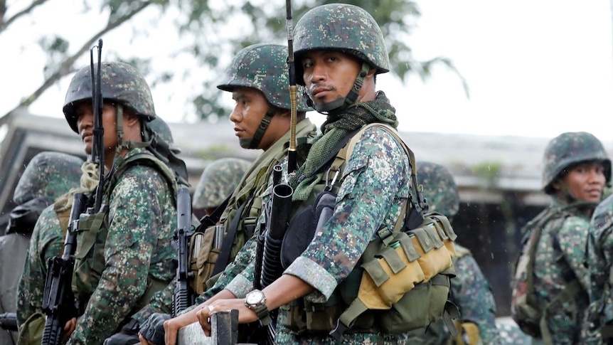 Philippine soldiers ride on a military vehicle while government forces continue their assault.