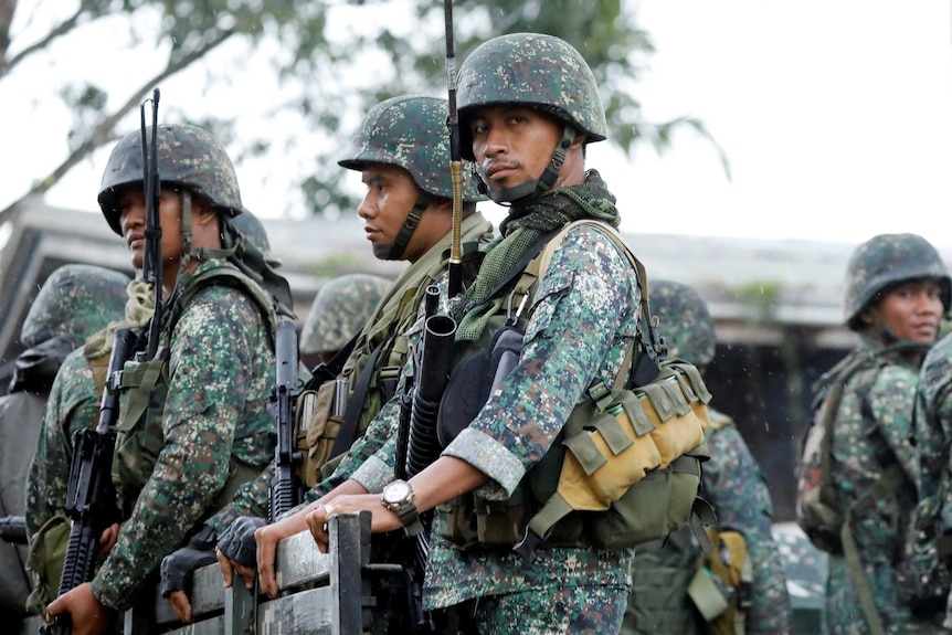 Philippine soldiers ride on a military vehicle while government forces continue their assault.