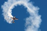 A plane leaves a smoke trail while it flies in a loop