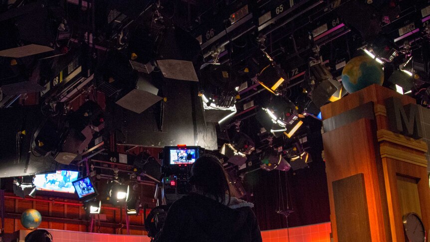 A camera operator films in a television studio.