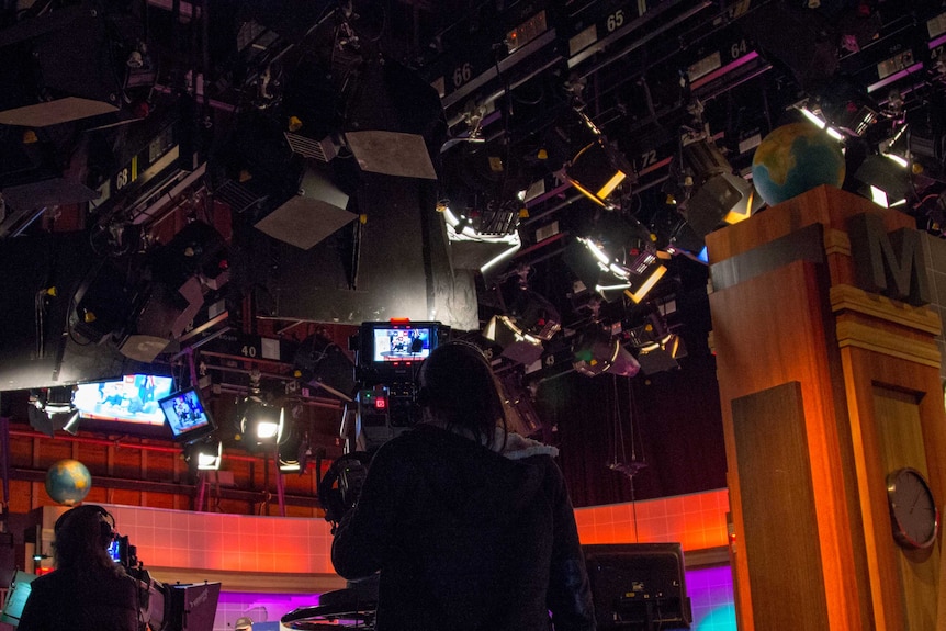 A camera operator films in a television studio.