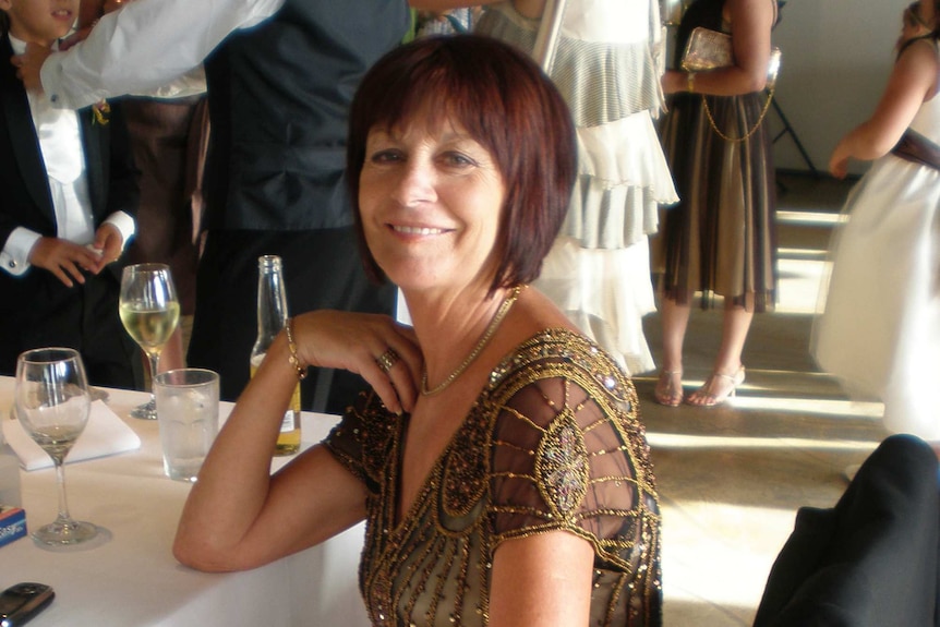 Joy Rowley sitting at a dinner table at a formal function smiling