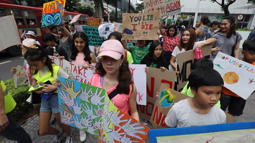 Students holding placards march on the streets of Bangkok.