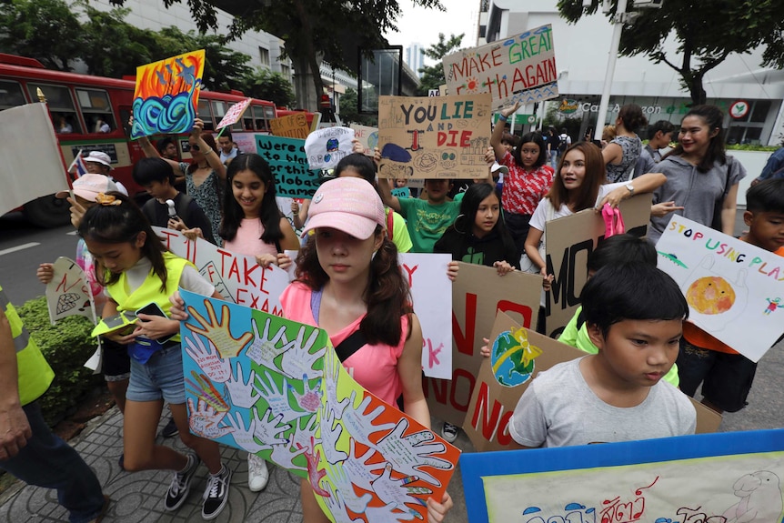 Students holding placards march on the streets of Bangkok.