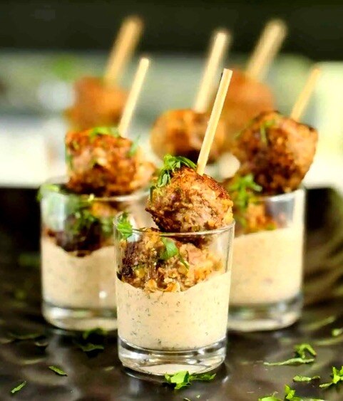 Lamb and mint balls on skewers in glasses with tzatziki dipping sauce