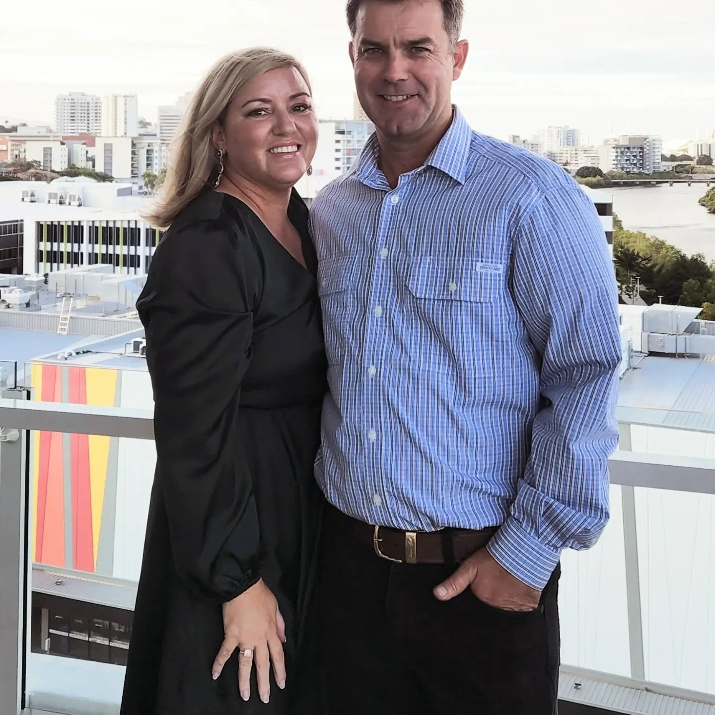 A woman and men stand together smiling, they are dressed up