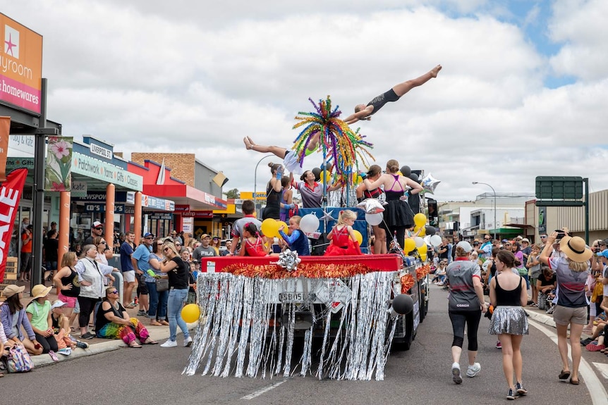 A street party parade with gymnasts on a display truck.