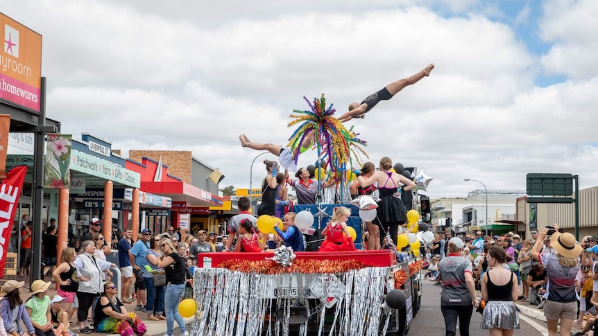 A street party parade with gymnasts on the display truck