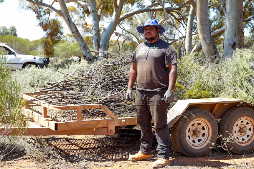 Jonas Donaldson next to a pill of shrub to be used to prevent soil erosion on Credo Station.