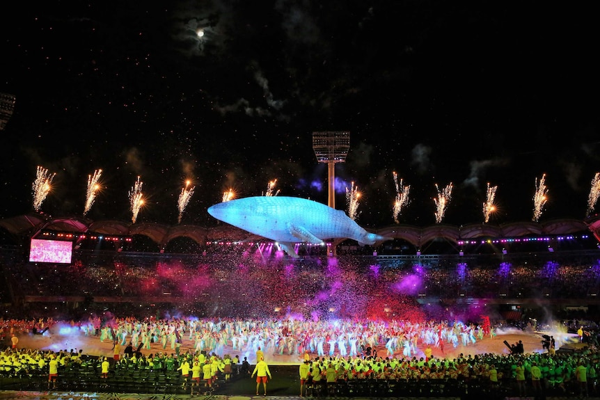 A large whale figure floats above the stadium while confetti and fireworks shoot out