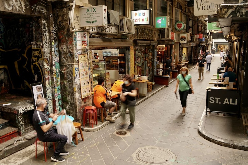 People walking in a laneway wearing masks.