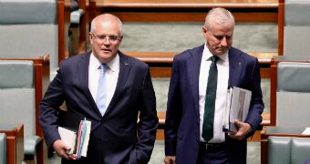 Two men in suits holding binders stride with purpose