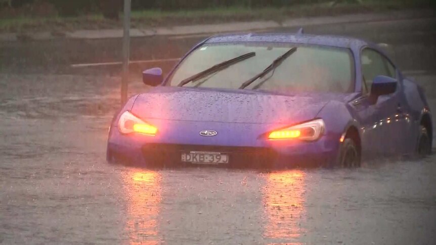a car caught in flood waters with its headlights on