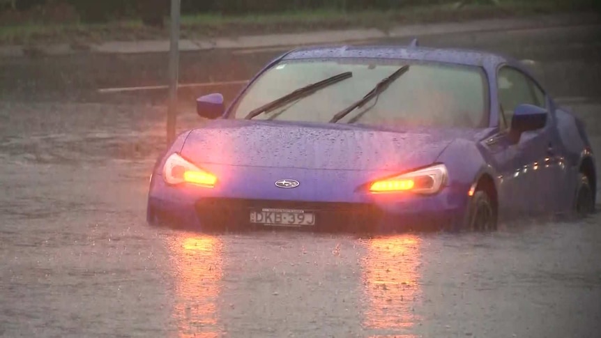 a car caught in flood waters with its headlights on
