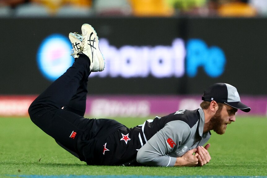 Kane Williamson dives with his hands cradled in his chest face down on the floor with his legs in the air
