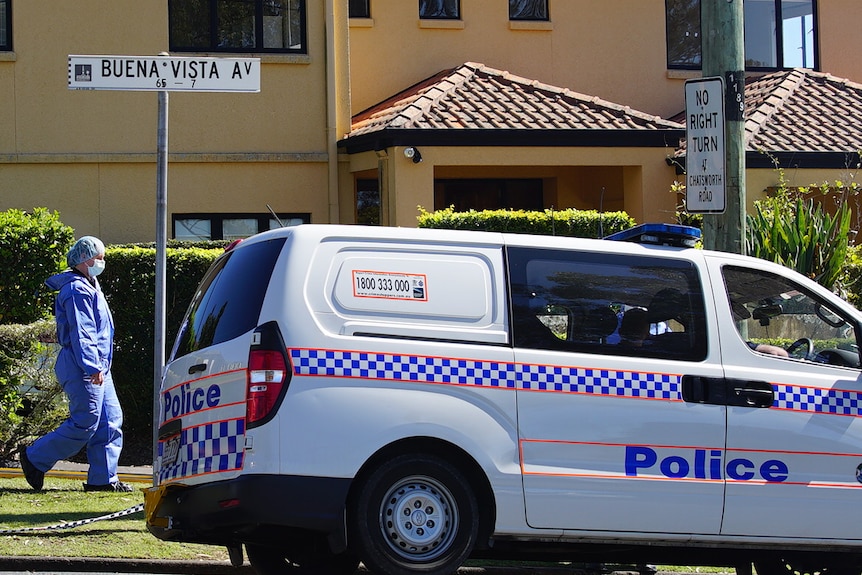 An officer in a hazmat suit walks past a police van.