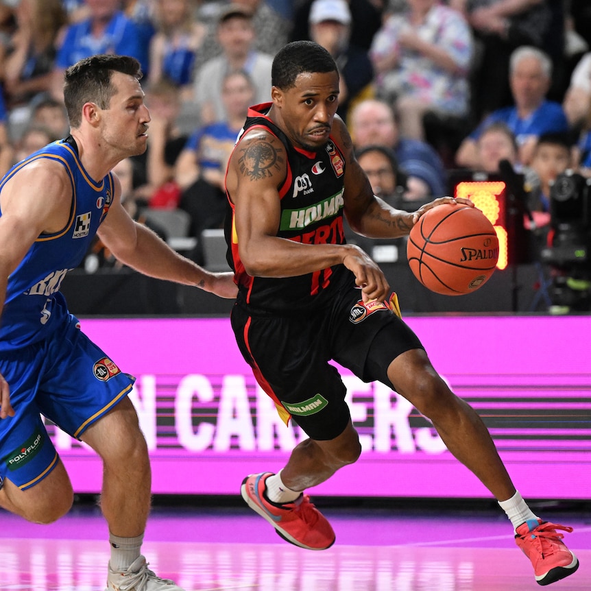 Bryce Cotton holds the ball while fending off his Brisbane Bullet's opponent.