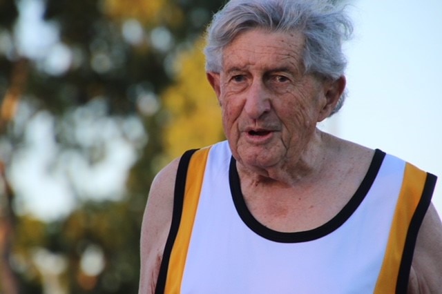 A close-up photo of an elderly man in a running singlet