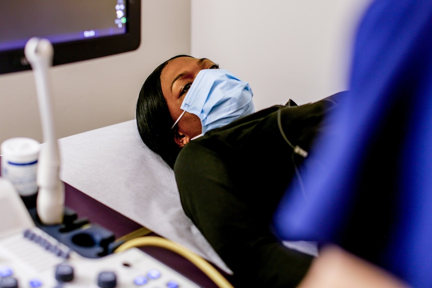 A woman lies on an ultrasound bed.