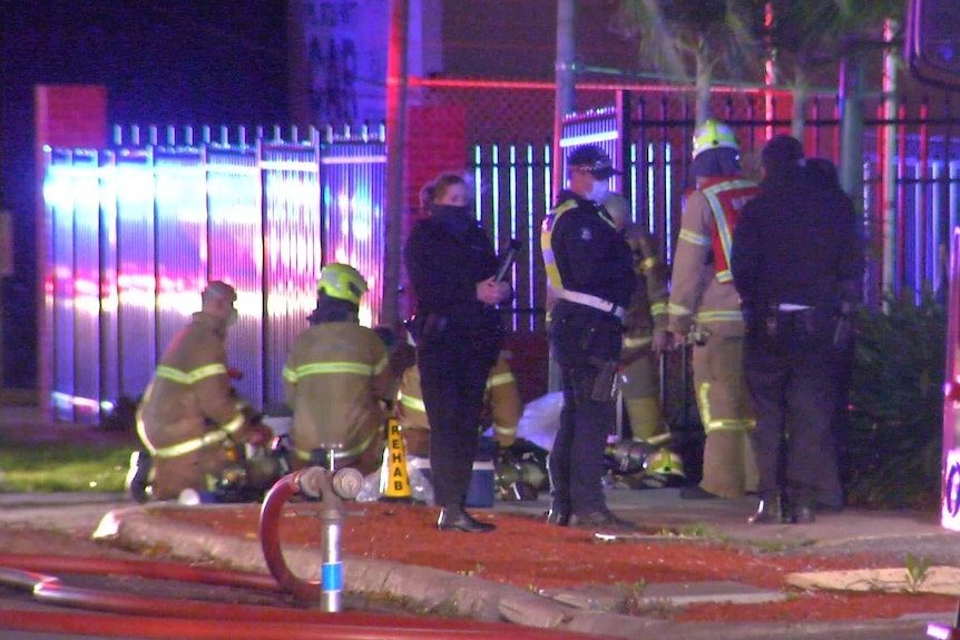 Fire and police officials on the sidewalk outside a home that was on fire.