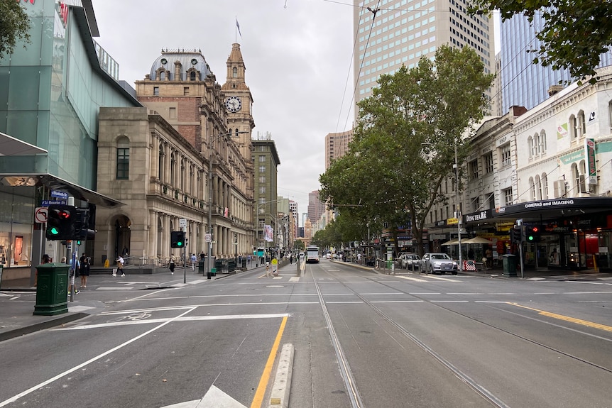 A largely empty Elizabeth Street, viewed from the tram tracks in the center of the road.