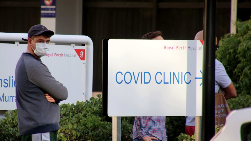 A man stands in a queue outside a COVID-19 fever clinic at Royal Perth Hospital with a face mask on.