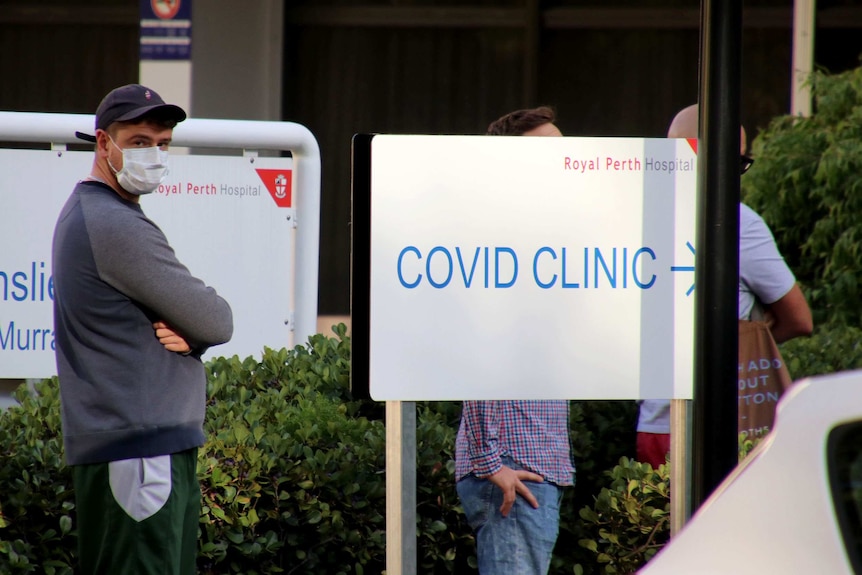 A man stands in a queue outside a COVID-19 fever clinic at Royal Perth Hospital with a face mask on.