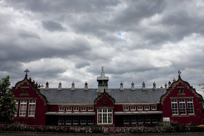 A red brick building with grey clouds above.