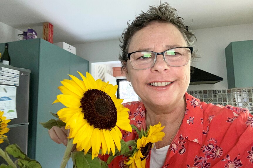 Woman smiling with sunflower nearby