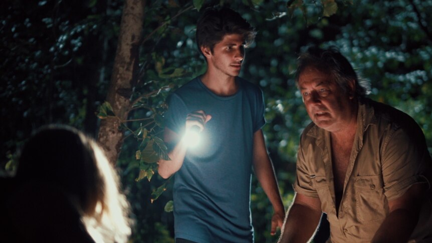A nighttime still from the film We're Family Now showing the titular family beneath a tree.