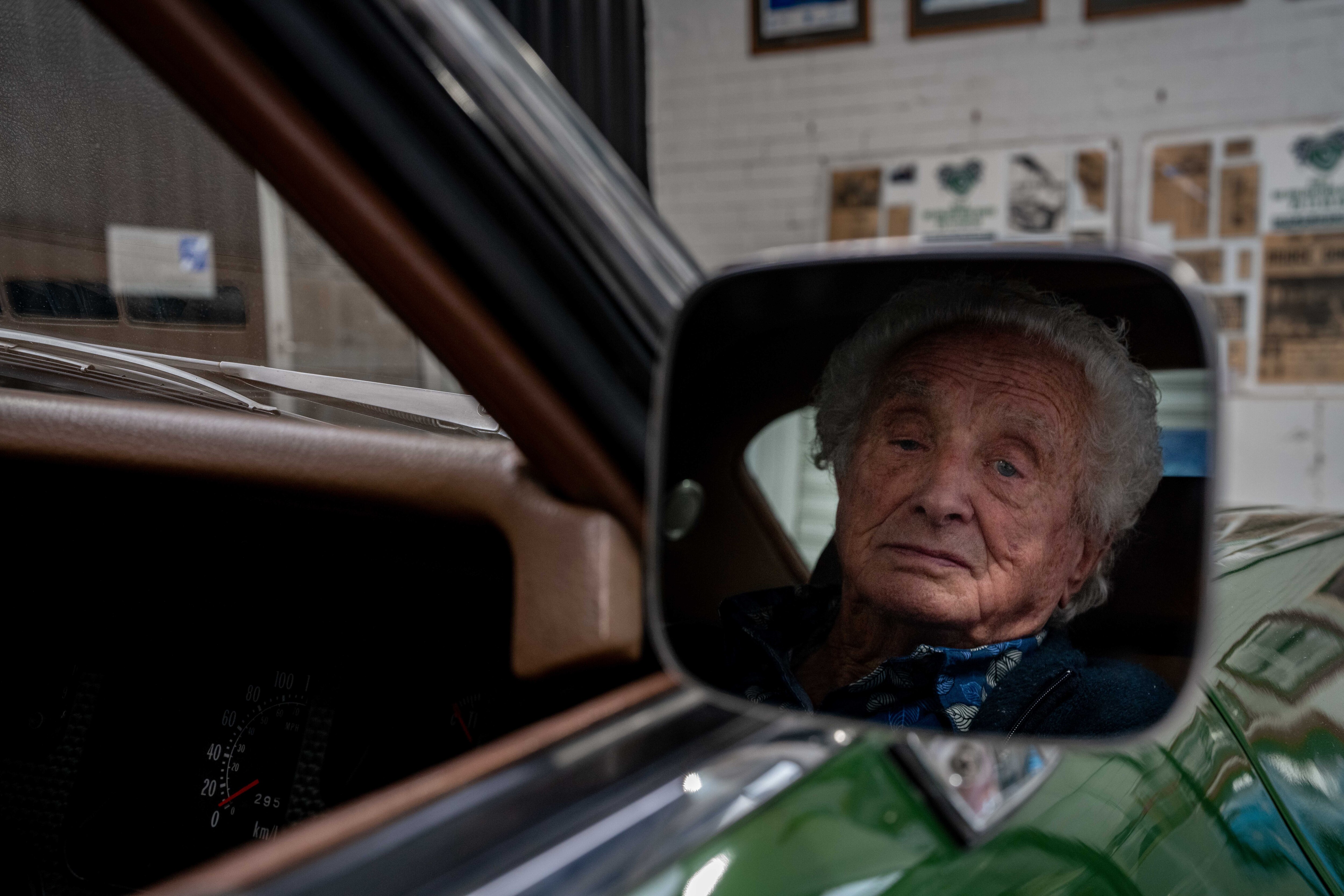 Man looking at side mirror of green car