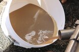 A white buck of brown dairy sludge being collected.