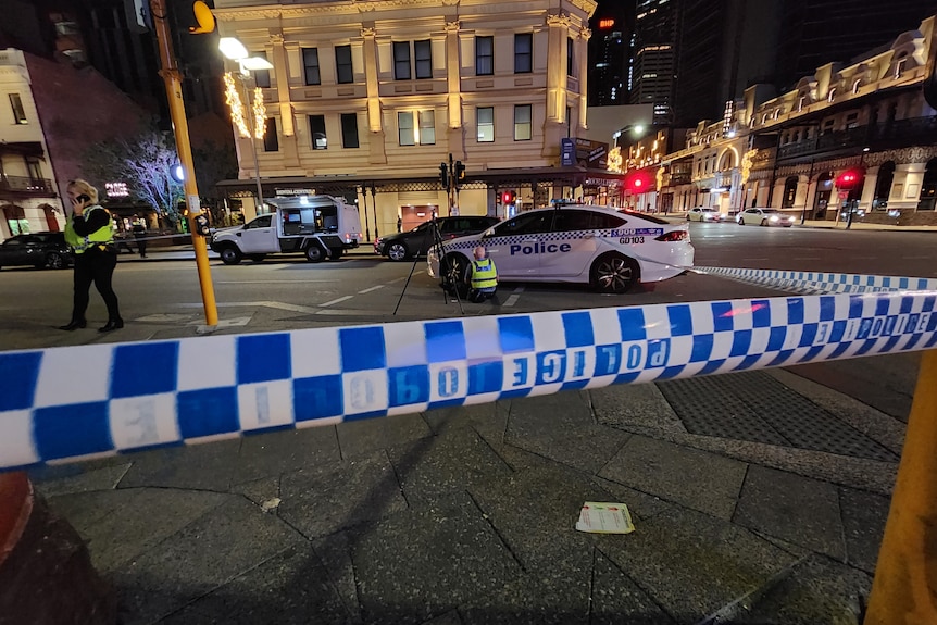 A police officer inspects a police car in an entertainment precinct