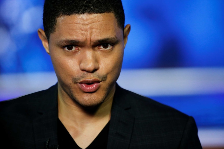 Close up image of Trevor Noah speaking with a frown on his face