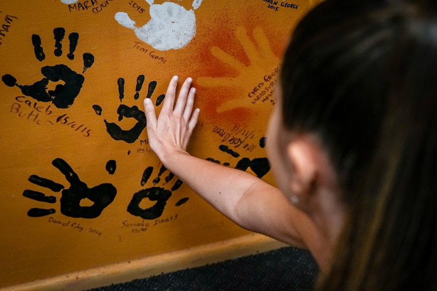 Holly Miller looks at her handprint on the wall.