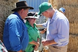 The PM talks with two graziers amongst hay bales in Cloncurry.