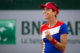A female tennis player wearing red, white and blue pumps her first during a match