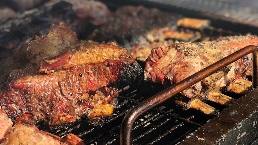 A close up of beef cooking on a grill.