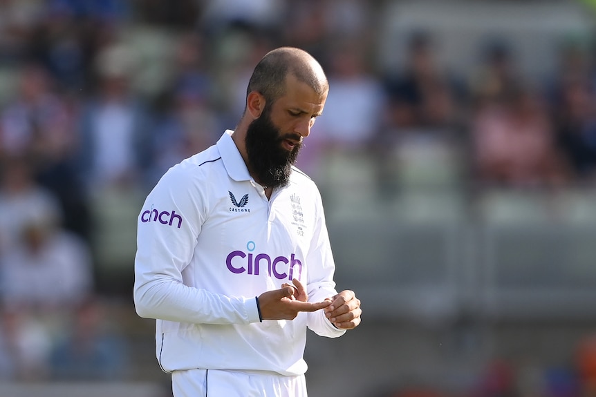 Moeen Ali looks at his finger