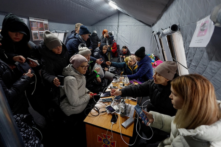 Kyiv residents charge their devices and warm up inside tent.