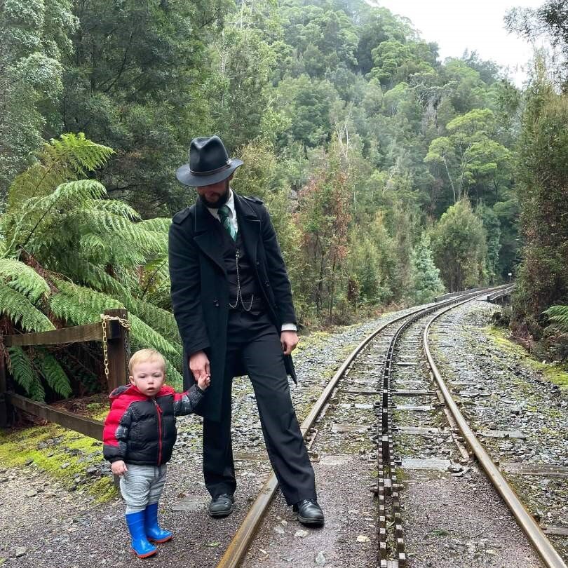 Tom Pavic-Ryan and his toddler son stand on the railway track in the forest