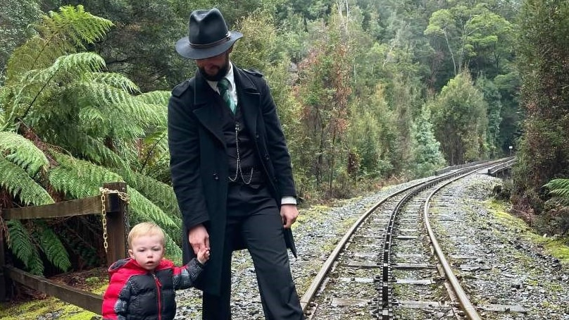 Tom Pavic-Ryan and his toddler son stand on the railway track in the forest