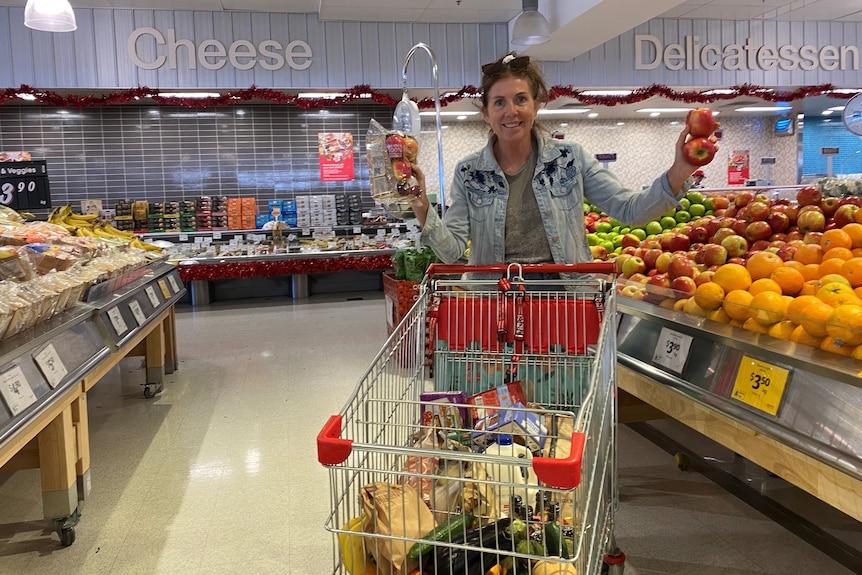 Jodie Hamilton holds up apples in a supermarket