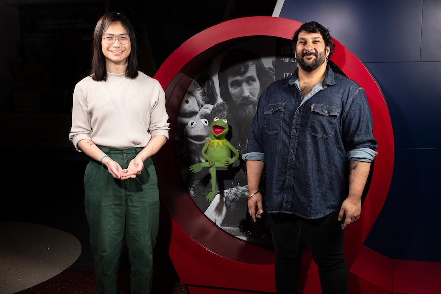 The researchers stand next to Kermit the Frog.